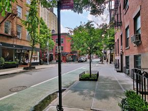 New York apartment for rent - a city street with buildings and trees and a street sign