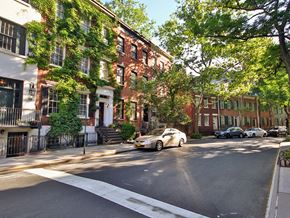 New York apartment for rent - a city street with a car parked in front of a row of houses