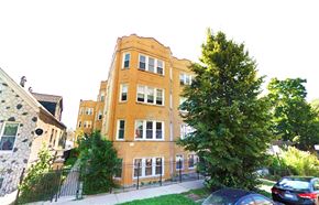 Chicago apartment for rent - a tall brick building with cars parked in front of it
