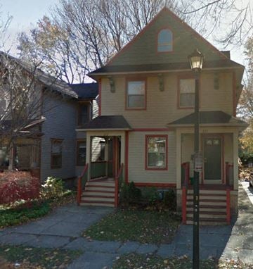 Rochester apartment for rent - a yellow house with red steps and a street light