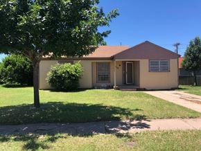 Abilene house for rent - A house with a brown roof and a tree in front.