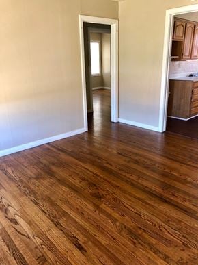 Abilene house for rent - A room with wooden flooring and a kitchen in the background.