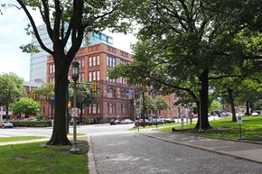 Harrisburg apartment for rent - A tree stands on a sidewalk in front of a brick building.