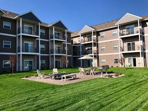 Owatonna apartment for rent - an exterior view of an apartment building with a picnic table and chairs