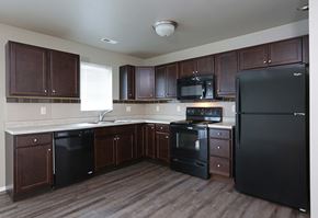 North Sioux City townhouse for rent - an empty kitchen with black appliances and dark wood cabinets