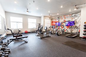 Sioux Falls apartment for rent - a gym with cardio machines and weights on the floor and a wall of graffiti