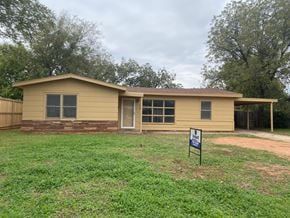 Abilene house for rent - a small yellow house with a sign in front of it
