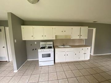 Abilene house for rent - a kitchen with white cabinets and a stove and a sink