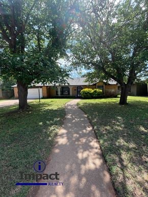 Abilene house for rent - A pathway in a park with trees on either side and a building in the background.