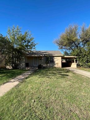 Abilene house for rent - A house with a brown roof and a white door is surrounded by a grassy lawn.