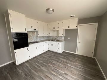Abilene house for rent - A kitchen with white cabinets and a black stove top oven.