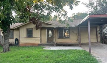 Abilene house for rent - a yellow house with a front porch and a tree
