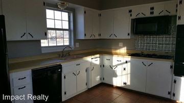 Abilene house for rent - a kitchen with white cabinets and a sink and a window