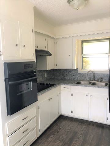 Abilene house for rent - A kitchen with white cabinets and a black oven.