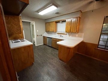 Abilene house for rent - A kitchen with wooden cabinets and a white countertop.