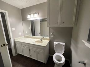 Abilene house for rent - A bathroom with a toilet, sink, and mirror.