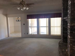 Abilene house for rent - an empty living room with windows and a ceiling fan