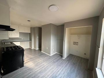 Abilene house for rent - an empty kitchen and living room with wood floors and white cabinets