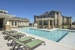 Austin apartment for rent - A pool with sun loungers and a building in the background.