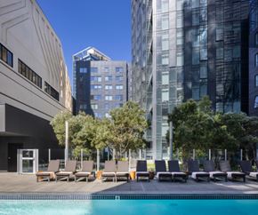 San Francisco apartment for rent - A pool surrounded by chairs and trees in front of a building.