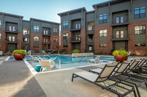 Greenville apartment for rent - a pool with lounge chairs in front of an apartment building