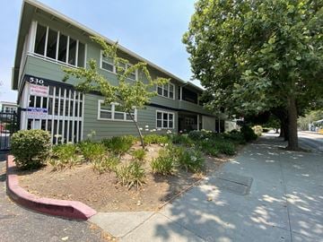 San Jose apartment for rent - a green building with a sidewalk and trees in front of it