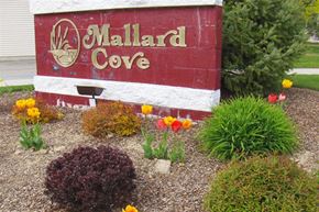 Caldwell apartment for rent - a sign for mallard cove with flowers in front of it