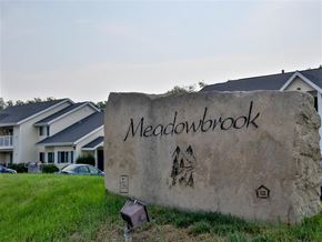 Emmett apartment for rent - a large stone sign in the grass with houses in the background