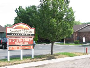Rupert apartment for rent - a sign in front of a parking lot with a tree