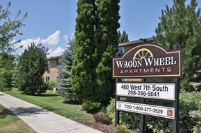 Rexburg apartment for rent - a sign for wagon apartments in front of a lawn and trees