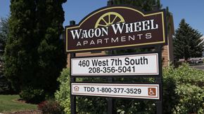 Rexburg apartment for rent - a sign for wagon apartments in front of a yard with trees