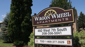 Rexburg apartment for rent - a sign for wagcon wheel apartments in front of a tree