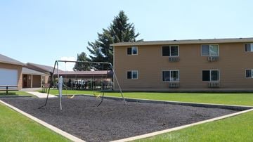 Rexburg apartment for rent - a swing set in a playground in front of a building