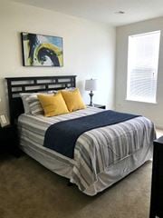 Westampton apartment for rent - a bedroom with a bed with a striped comforter and yellow pillows