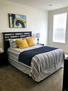 Westampton apartment for rent - a bedroom with a bed with a striped comforter and yellow pillows