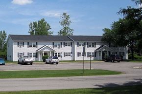 Sanborn apartment for rent - a large white building with cars parked in front of it