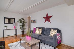 Tonawanda apartment for rent - A living room with a grey couch, a wooden coffee table, and a red star on the wall.