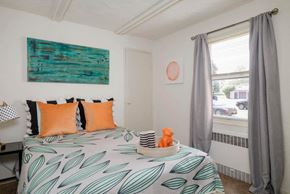 Tonawanda apartment for rent - A bedroom with a bed covered in a leaf patterned bedspread.