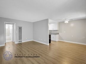 Long Beach apartment for rent - A spacious room with wooden flooring and a logo for Beach Front Property Management.