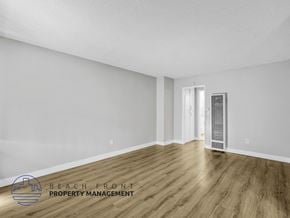 Long Beach apartment for rent - A spacious room with wooden flooring and white walls, with a door on the right side.