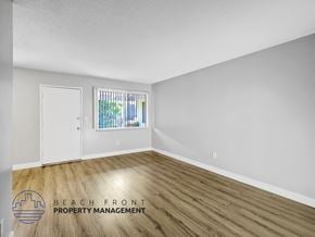 Long Beach apartment for rent - A room with wooden flooring and a window with bars on it.