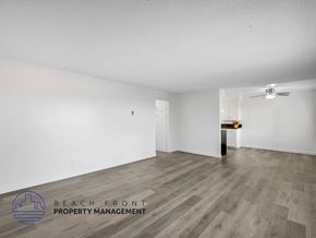 Long Beach apartment for rent - A spacious room with wooden flooring and a ceiling fan, managed by Beach Front Property Management.