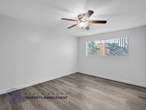 Long Beach apartment for rent - A room with a ceiling fan and a window showing a view of a building and trees.