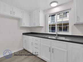 Long Beach apartment for rent - A kitchen with white cabinets and a black countertop.