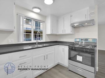 Long Beach apartment for rent - A kitchen with a stove top oven and a window with a view of a balcony.