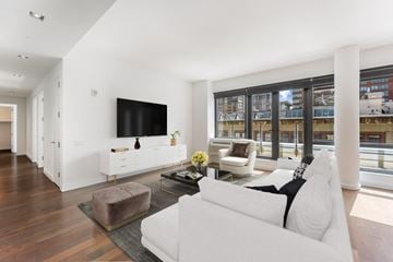 Jersey City apartment for rent - A modern living room with a white couch and a flat screen TV mounted on the wall.