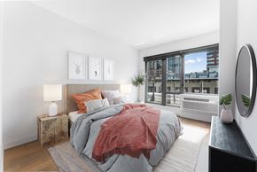 Jersey City apartment for rent - A bedroom with a large bed and a view of the city.