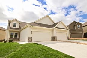Shawnee triplex for rent - a beige house with a garage and a lawn