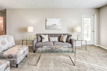 Palatine apartment for rent - A living room with a grey couch, a glass coffee table, and a painting on the wall.