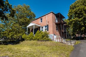 New Haven apartment for rent - A red brick house with a white porch and a balcony on the second floor.